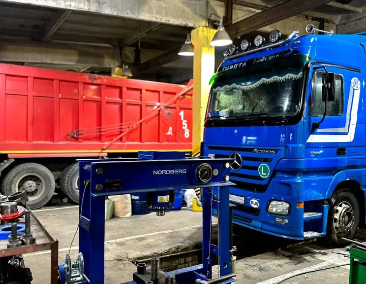 Гидравлический пресс в цехе автосервиса, на фоне тягач Mercedes Actros