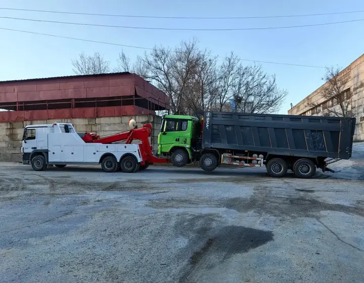 Грузовой эвакуатор доставил в автосервис самосвал с прицепом